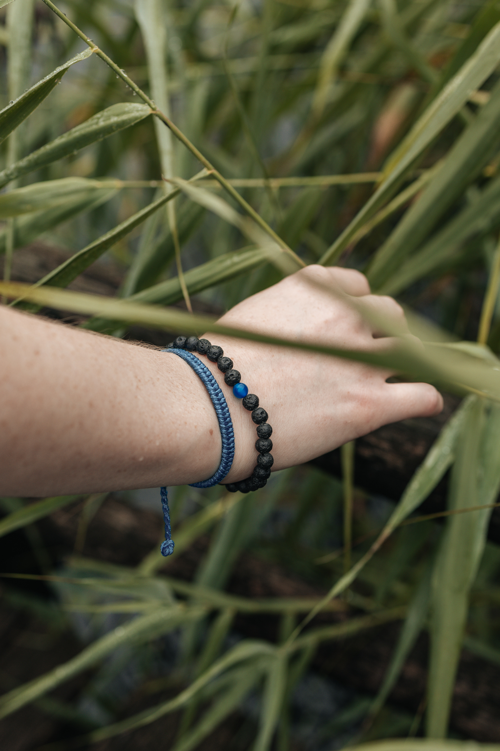Blue beaded braided bracelet on wrist with adjustable clasp and charm