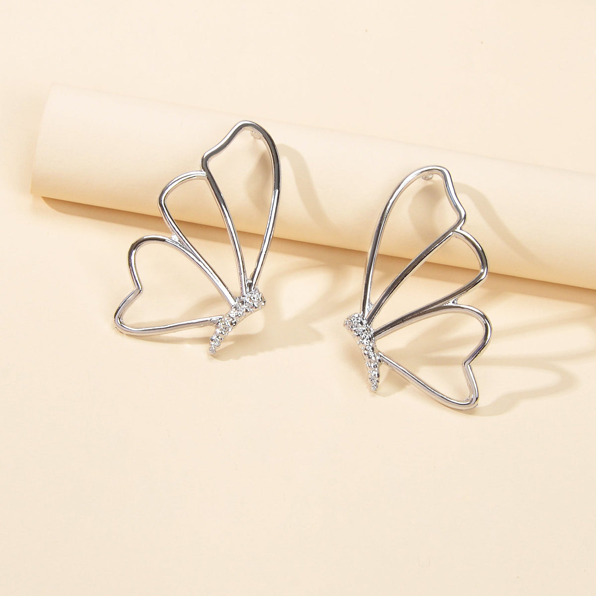Silver hollow butterfly stud earrings with four wing arcs and rhinestone accents