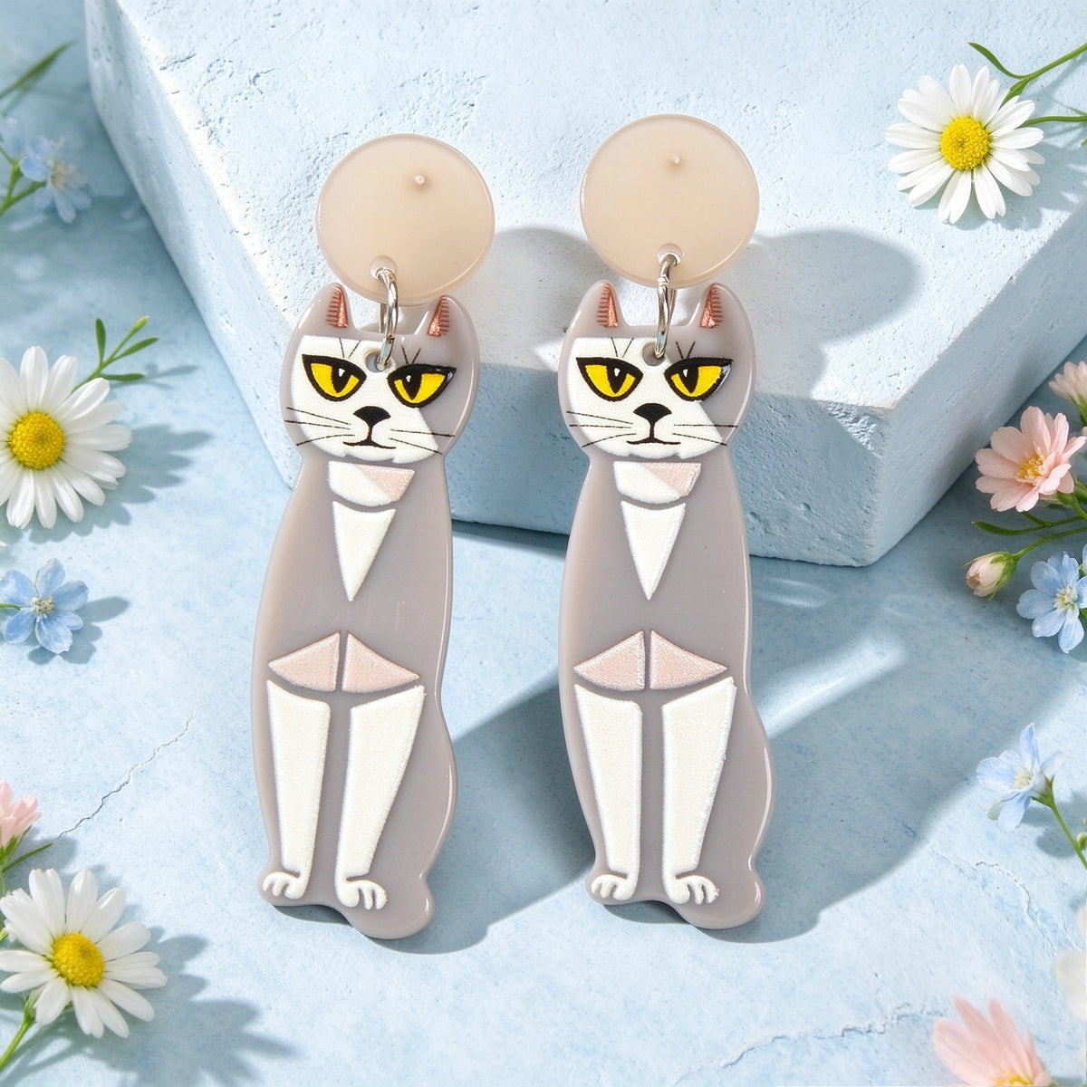 Pair of grey acrylic cat dangle earrings with gold hoops and yellow-eyed faces