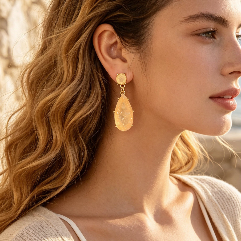 Gold-tone teardrop earrings with peach faux gemstone drop and round stud top.