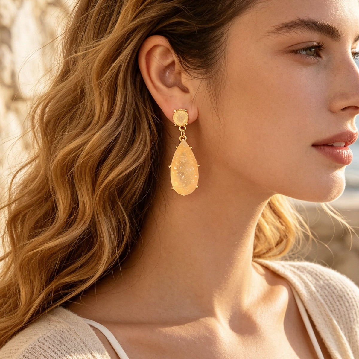 Gold-tone teardrop earrings with peach faux gemstone drop and round stud top.