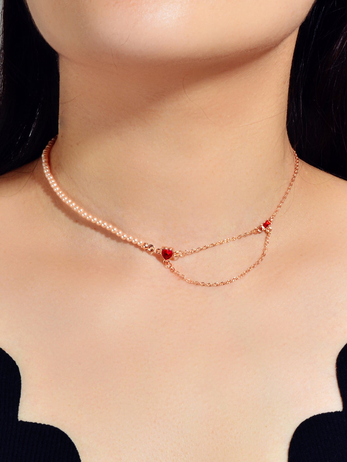 Rose gold tone chain necklace worn on neck, red crystal heart centerpiece