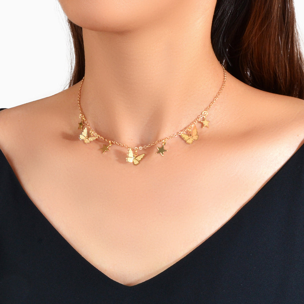 Gold-tone collar necklace with small star and butterfly charms along neckline