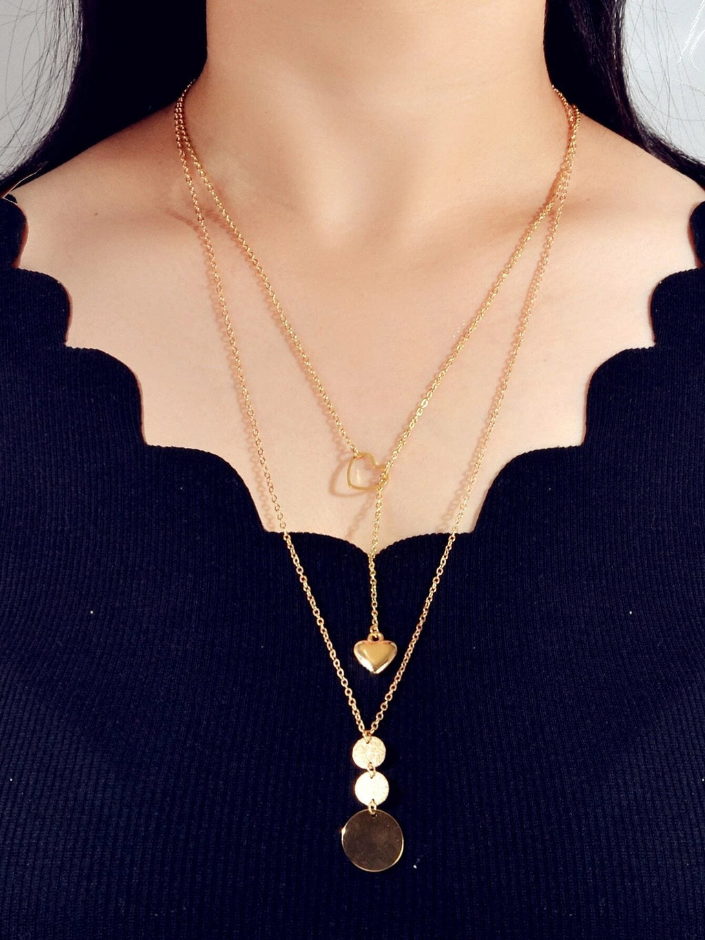 Gold-tone layered necklace on model with heart pendants and round discs