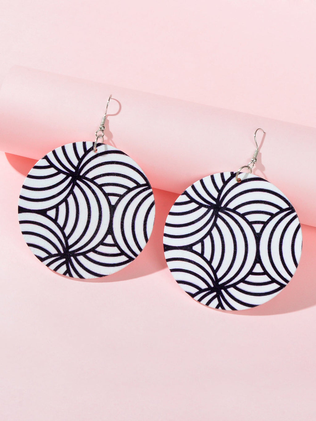Two round zebra swirl drop earrings, black and white, hanging on silver hooks