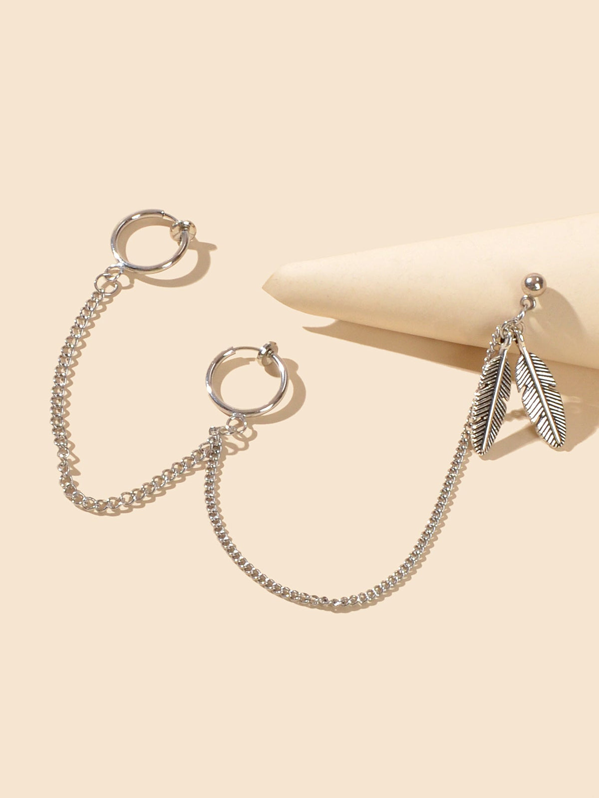 Silver-tone ear cuffs with long chain and feather charm, two pieces shown