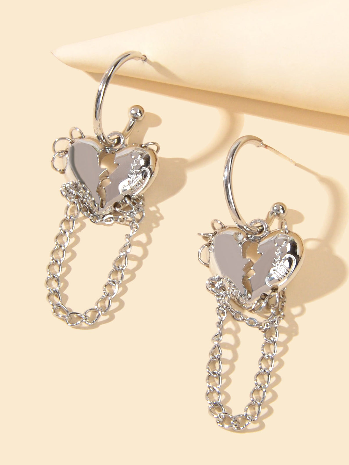 Silver hoop earrings with layered heart charms and dangling chain links