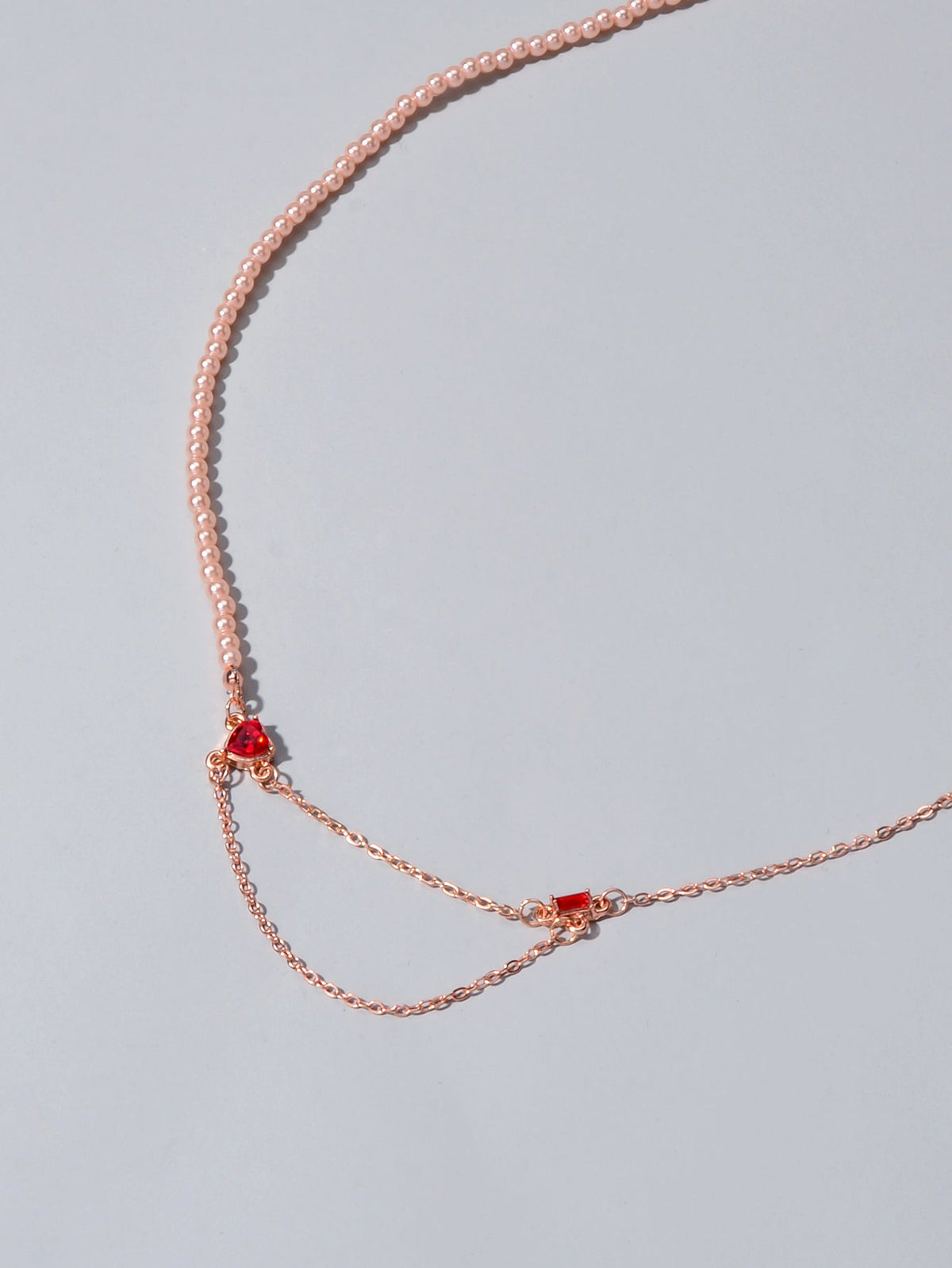 Rose gold tone chain necklace with red crystal accents and heart-shaped setting