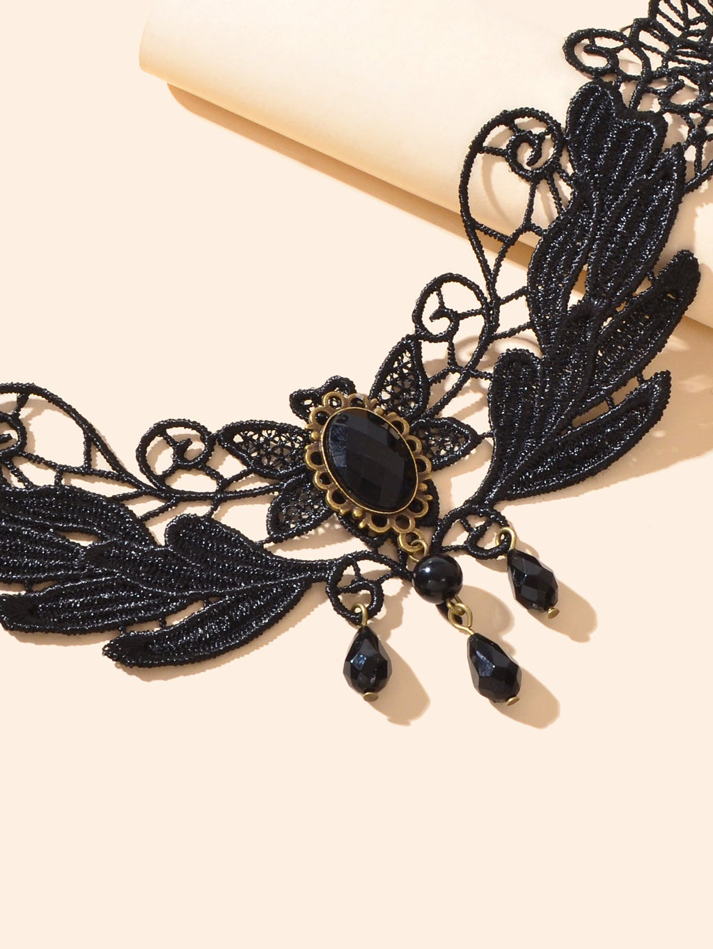 Black lace leaf choker detail with oval cabochon, gold filigree, and teardrop charms