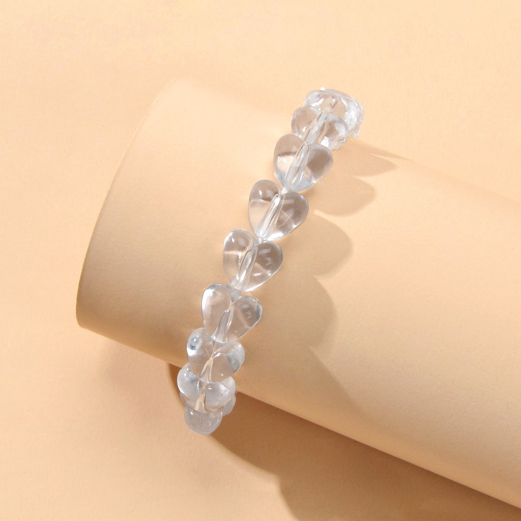 Clear heart-bead elastic bracelet on wrist, stacked transparent resin heart beads