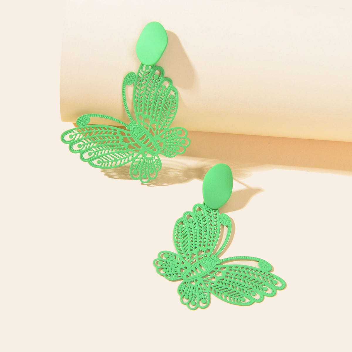 Green hollow butterfly stud earrings with large winged charm, angled view