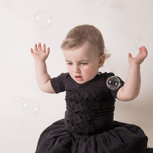 Black baby onesie with spiderweb lace detail worn by toddler, short sleeves