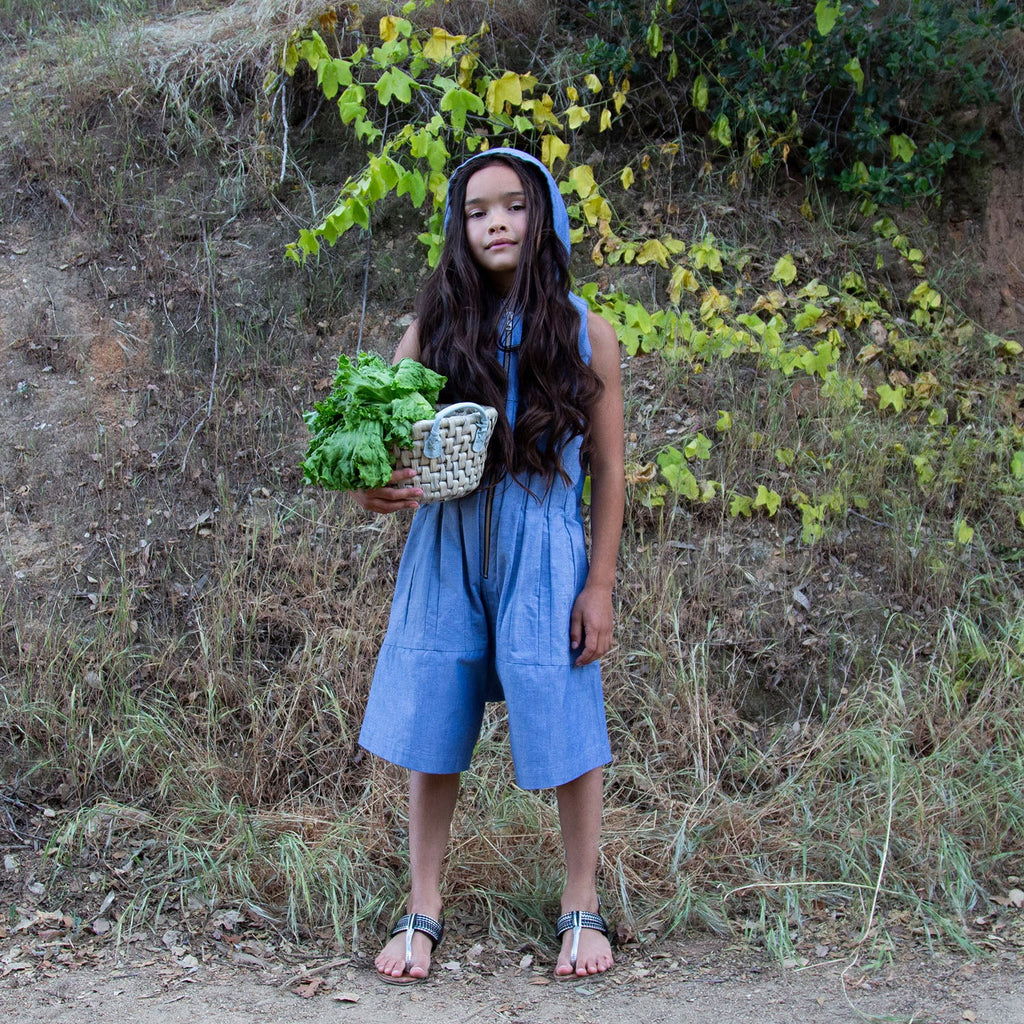 Blue denim hooded sleeveless jumpsuit worn with wide legs and side pockets