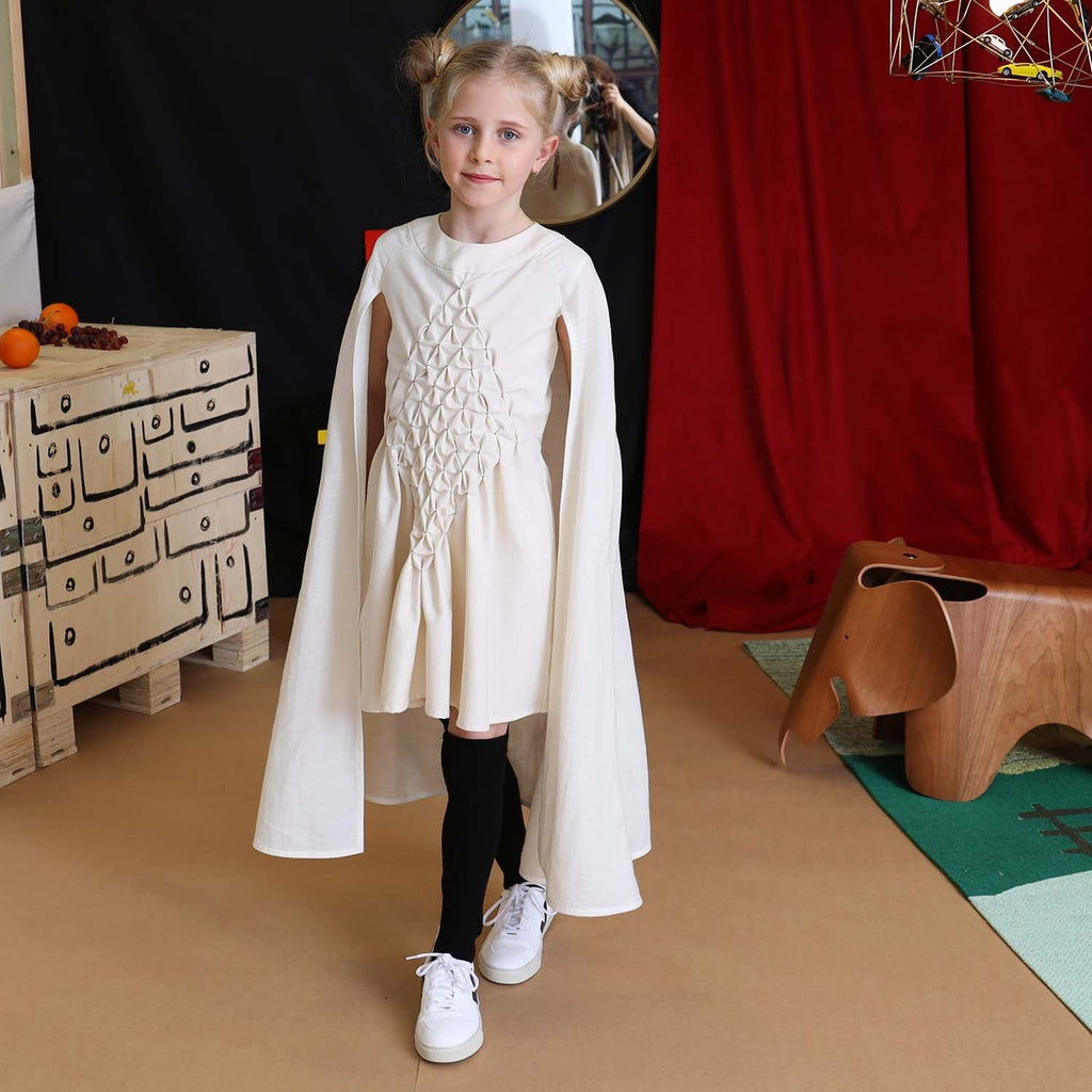 Girls' white smock dress with attached cape, full-length front view
