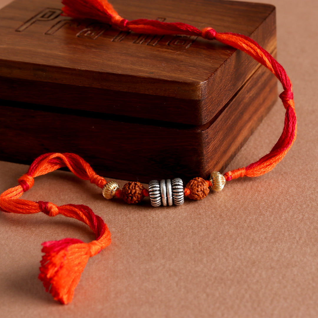 Rakhi with red–orange thread and rudraksha beads with silver barrel spacers
