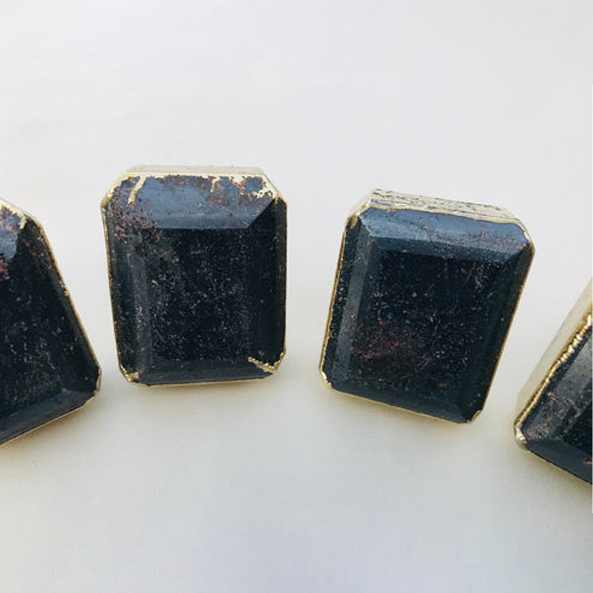 Dark gemstone cabinet pull with gold-toned frame, faceted octagonal cube, metal post