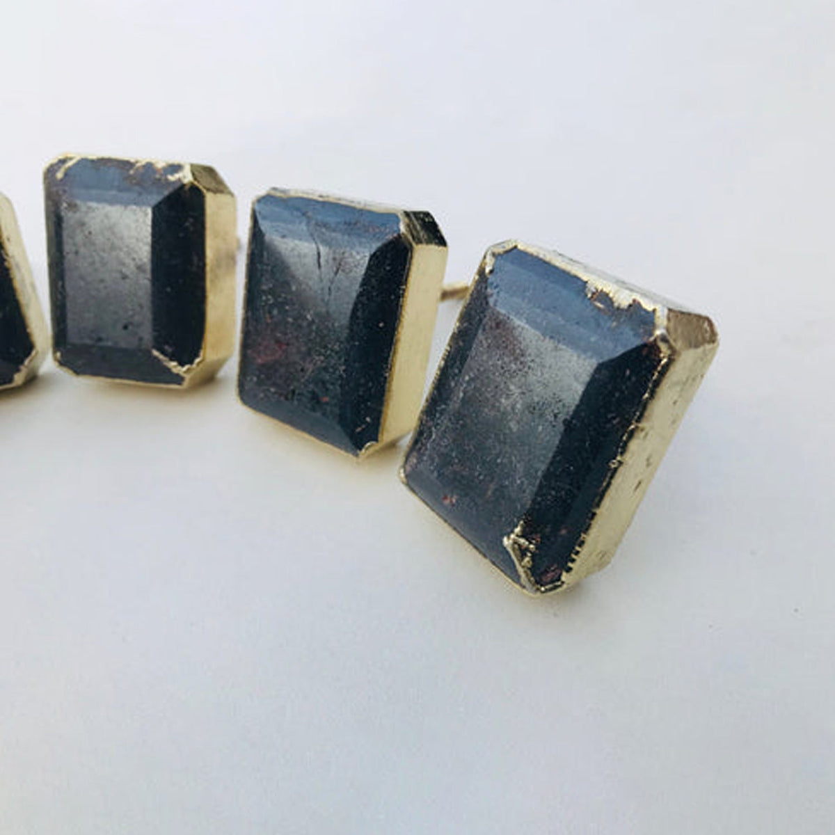 Set of dark gemstone drawer pulls with gold-toned edges, faceted cube shapes, metal posts