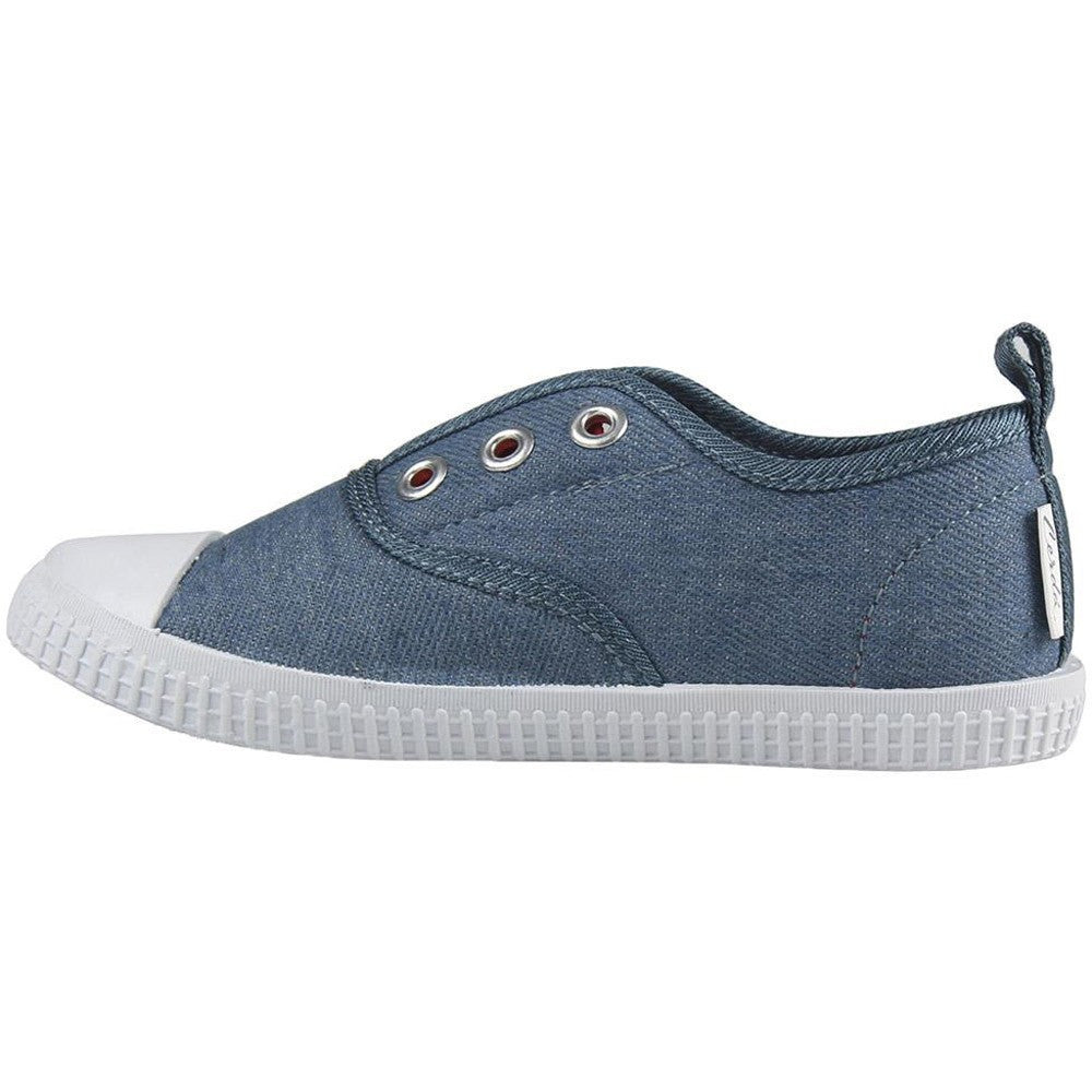 Side view of blue canvas low-top sneaker with lace eyelets, logo patch, and white sole