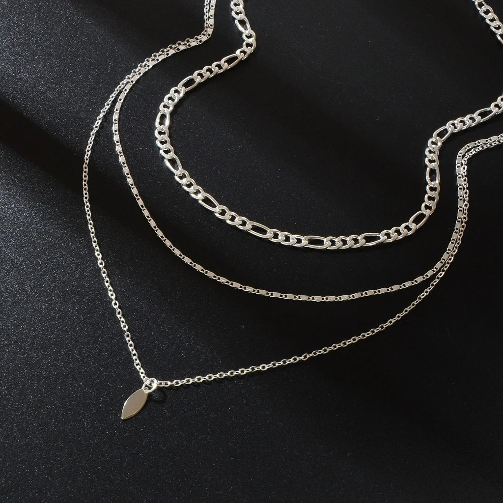 Close-up layered silver-tone choker necklace with small leaf drop charm on chain