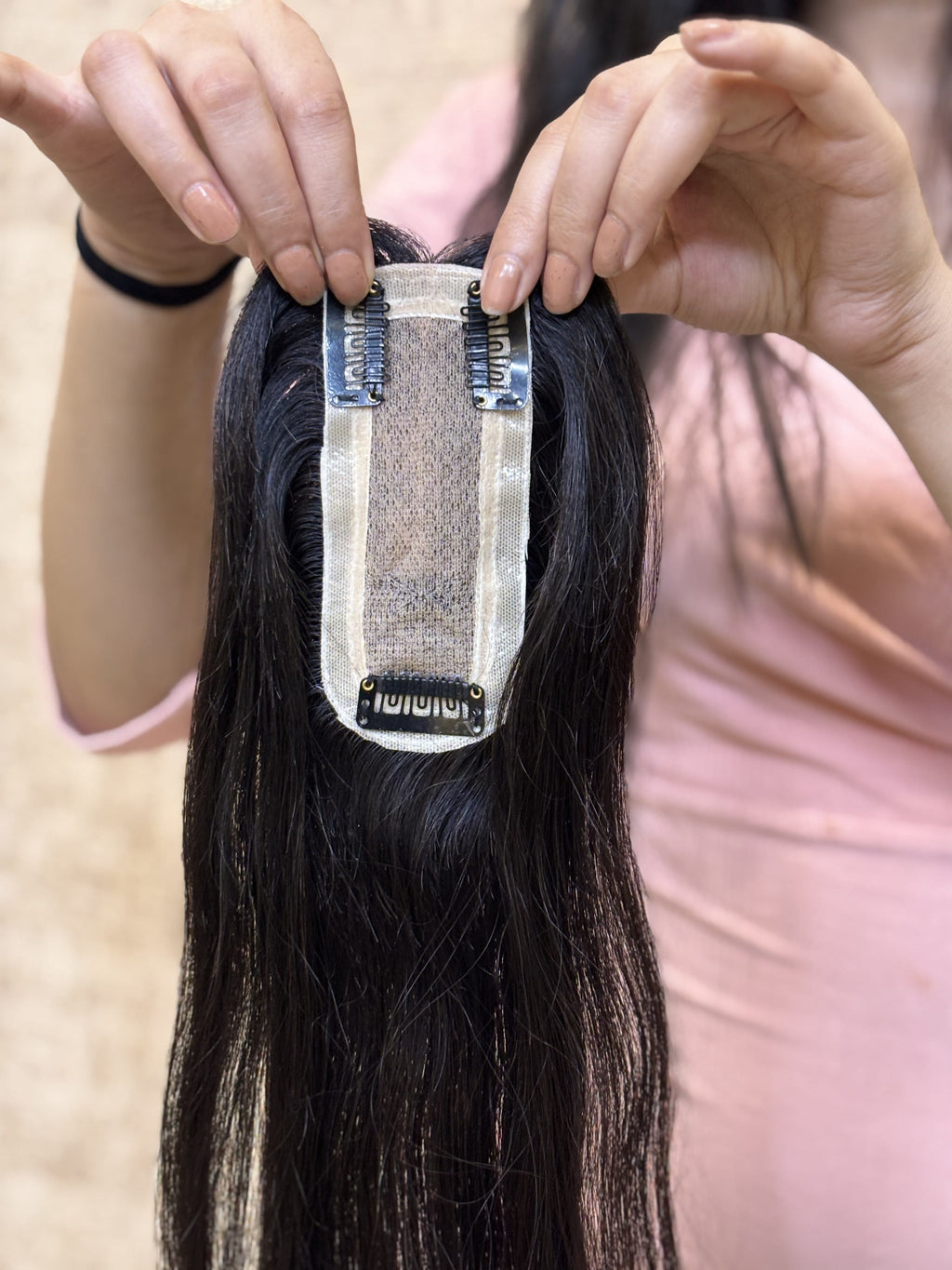 Natural black straight hair patch held up, showing beige silk base and root area.