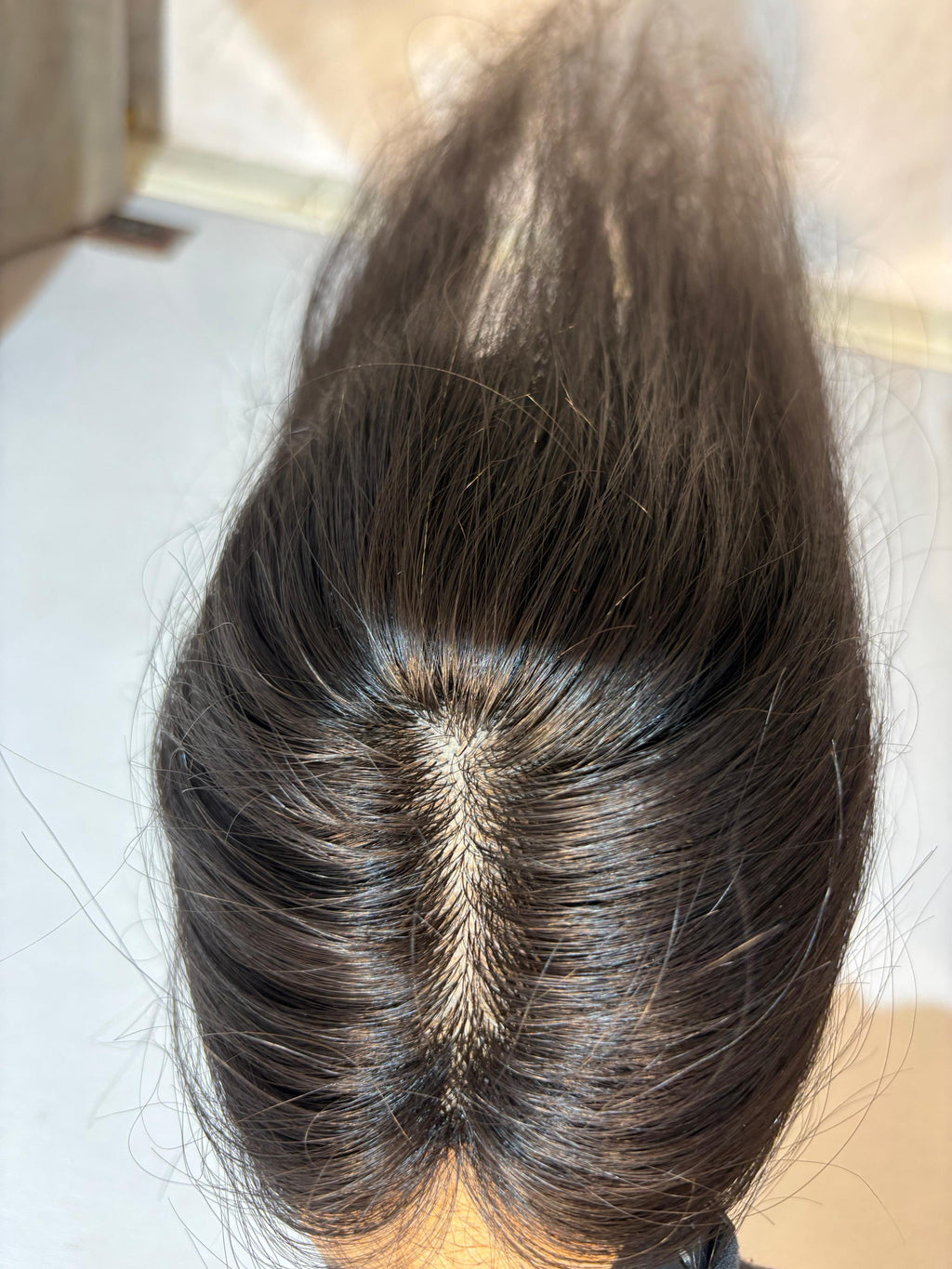 Natural black straight hair patch with visible silk base center parting.