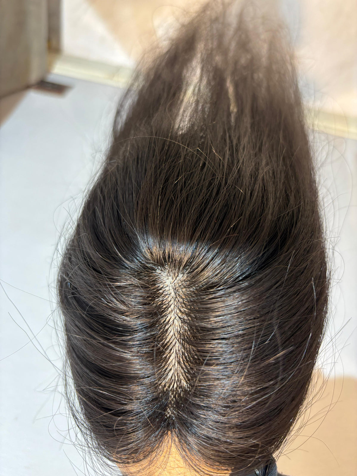 Natural black straight hair patch with visible silk base center parting.